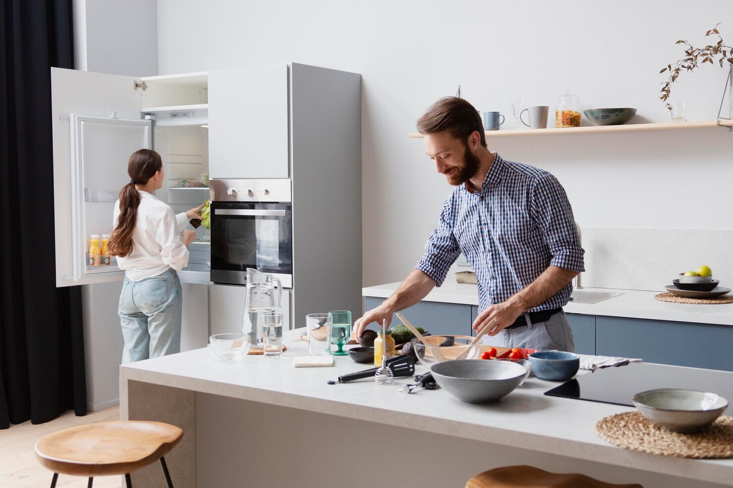 Two people prepare food together in a bright kitchen, matching the idea of planning meals and distributing calories more intentionally.