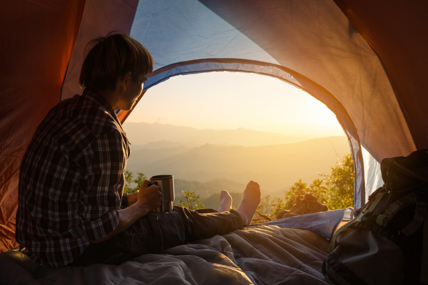An unmade bed with white rumpled sheets and two gray pillows sits beneath a window with closed blinds, allowing soft daylight to filter into the dimly lit room. The atmosphere feels quiet, restful, and slightly somber, suggesting early morning or a peaceful moment of solitude.